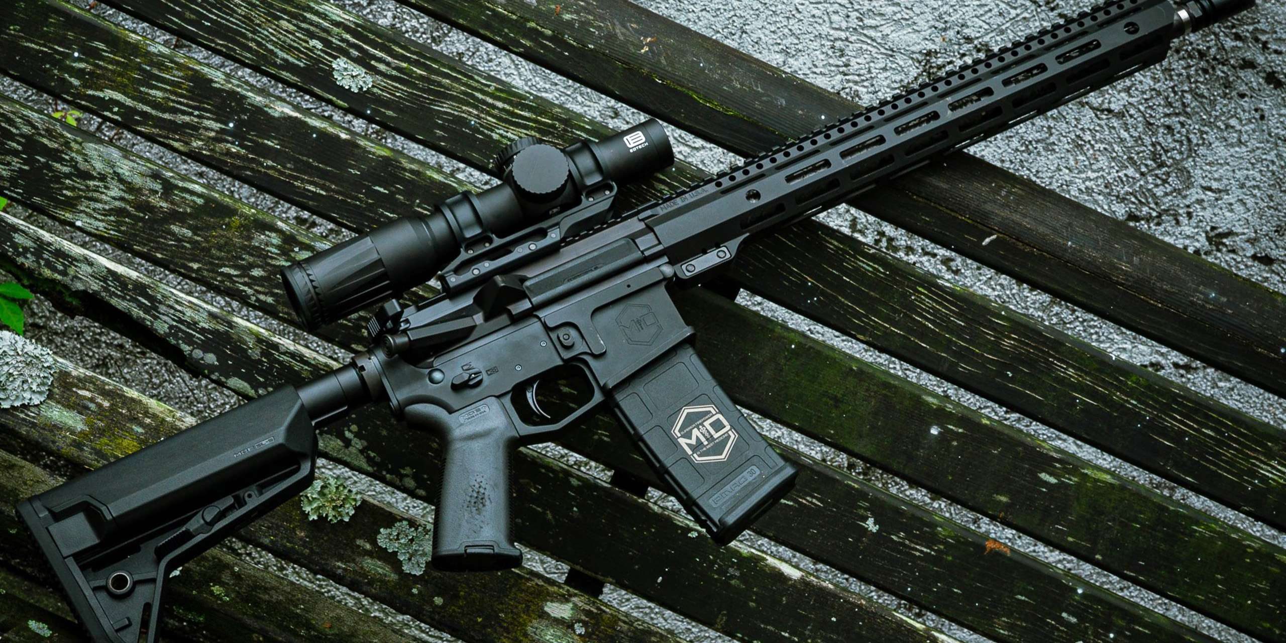 SOIDC DOC AR15 with scope leaned against wood bench